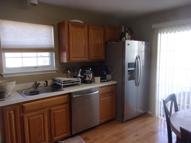 kitchen with brown cabinetry, appliances with stainless steel finishes, light countertops, and a sink