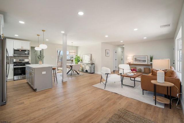 living room with recessed lighting, baseboards, visible vents, and light wood finished floors