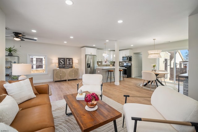 living area with light wood-type flooring, baseboards, a ceiling fan, and recessed lighting