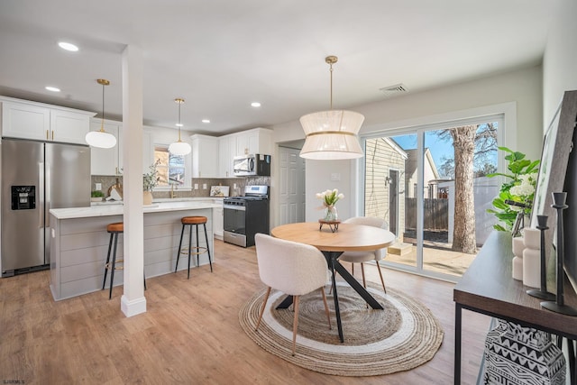 dining area with light wood-type flooring, visible vents, and recessed lighting