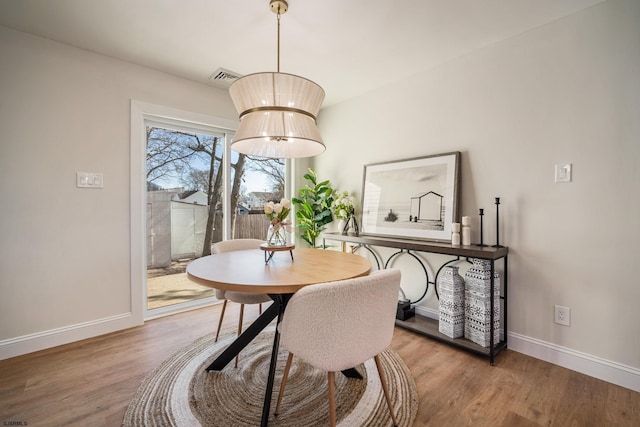 dining area featuring visible vents, baseboards, and wood finished floors