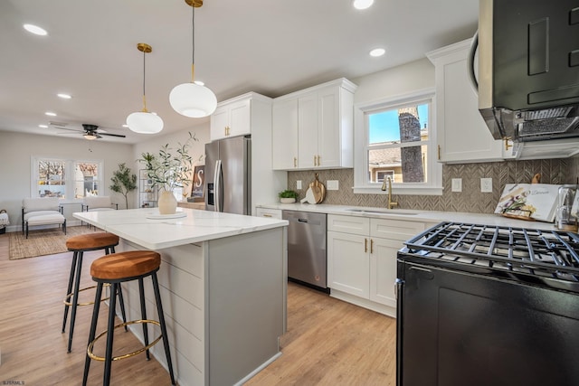 kitchen featuring appliances with stainless steel finishes, open floor plan, white cabinets, and a sink