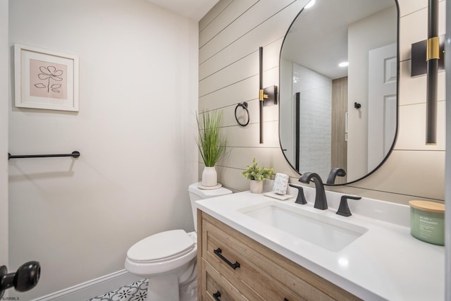 bathroom with toilet, baseboards, and vanity