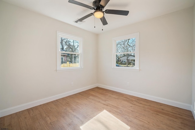 empty room with light wood finished floors, baseboards, visible vents, and a ceiling fan