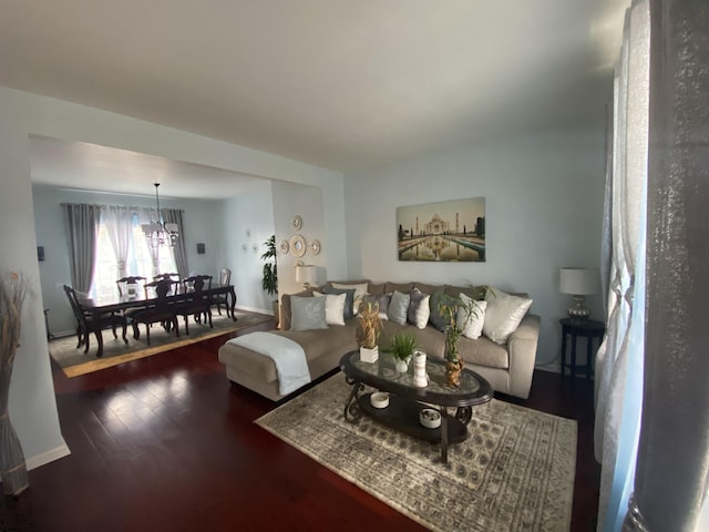 living room featuring dark wood finished floors, baseboards, and an inviting chandelier