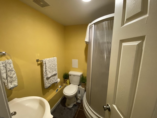 bathroom featuring visible vents, toilet, a sink, a shower stall, and tile patterned floors