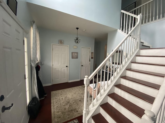 entrance foyer with dark wood-style floors, baseboards, and stairs