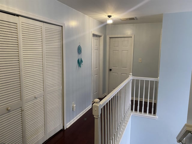 hall with baseboards, visible vents, and wood finished floors