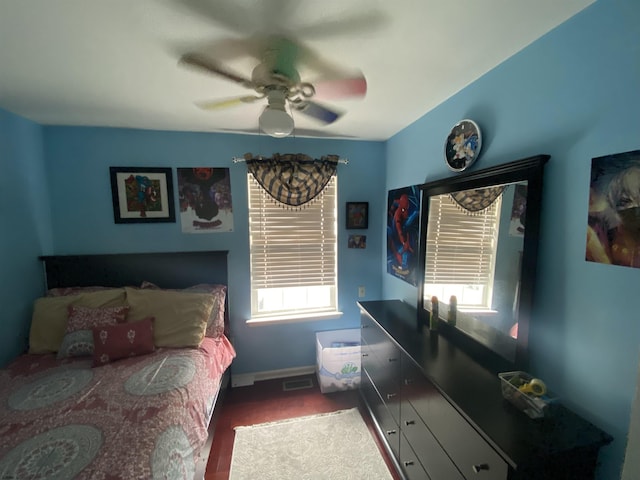 bedroom with ceiling fan, multiple windows, visible vents, and dark wood-style flooring