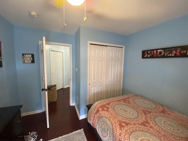 bedroom featuring a closet, dark wood finished floors, a ceiling fan, and baseboards