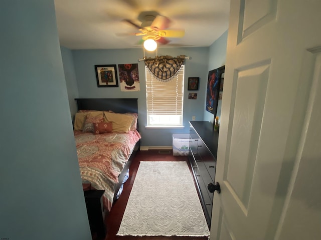 bedroom with dark wood-type flooring, a ceiling fan, and baseboards