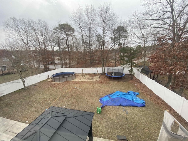 view of yard with a trampoline, a fenced backyard, and a fenced in pool