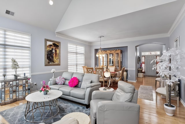 living area with ornamental molding, arched walkways, visible vents, and wood finished floors