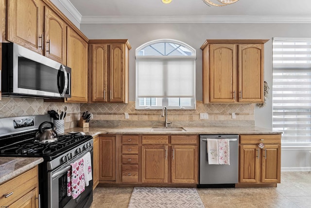 kitchen with light stone countertops, stainless steel appliances, a sink, ornamental molding, and decorative backsplash