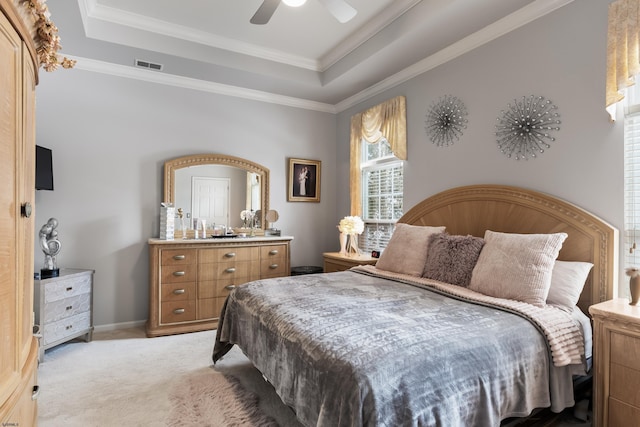 bedroom with light carpet, a tray ceiling, visible vents, and crown molding