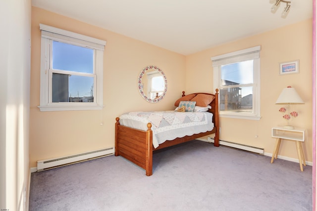 bedroom with a baseboard heating unit, light carpet, and baseboards