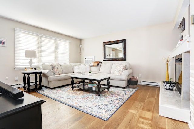 living area featuring a baseboard radiator, a tiled fireplace, wood finished floors, and a wall mounted air conditioner