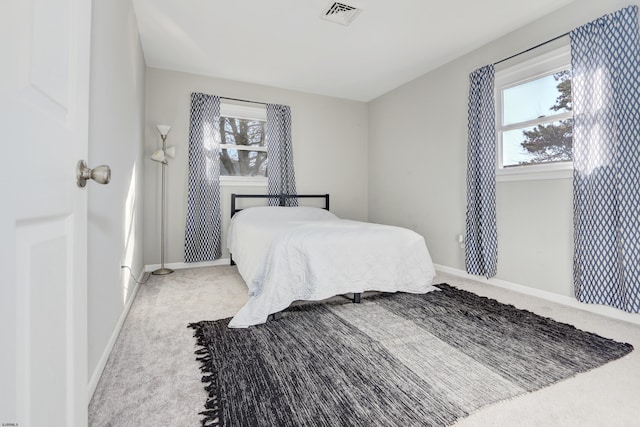 carpeted bedroom with visible vents, baseboards, and multiple windows