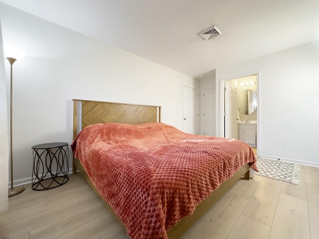 bedroom featuring light wood-style flooring, connected bathroom, visible vents, and baseboards