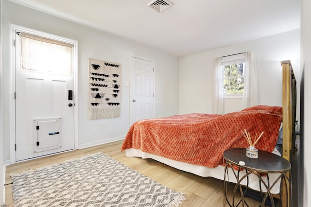 bedroom with baseboards, visible vents, and wood finished floors