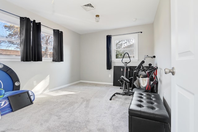 exercise area featuring light carpet, visible vents, baseboards, and a wealth of natural light