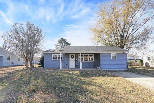 single story home featuring driveway, covered porch, fence, and a front lawn