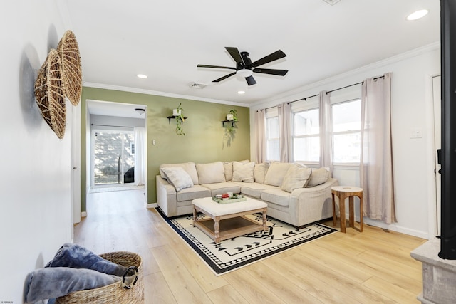 living room featuring ceiling fan, visible vents, crown molding, and wood finished floors