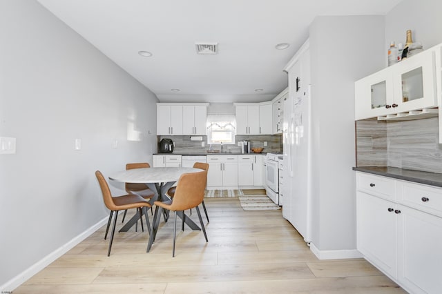 kitchen with dark countertops, visible vents, white cabinetry, and glass insert cabinets