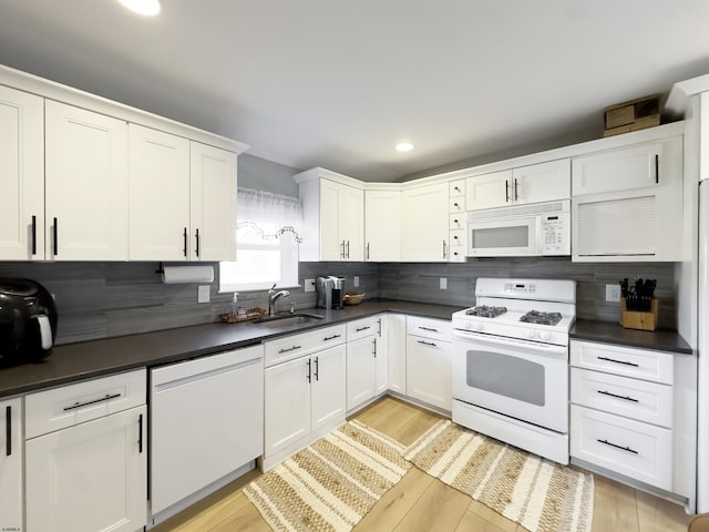 kitchen featuring white appliances, dark countertops, and white cabinets