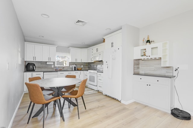 kitchen featuring white appliances, dark countertops, backsplash, and white cabinetry