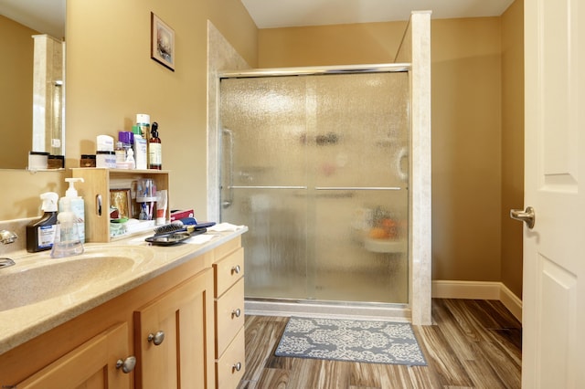 full bathroom with a stall shower, wood finished floors, and vanity