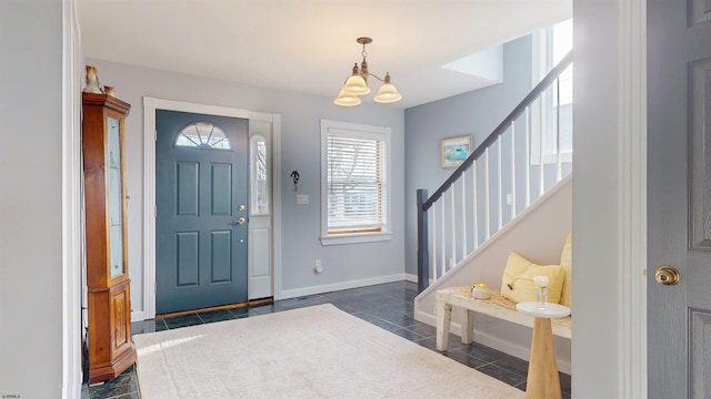 entryway featuring dark tile patterned floors, baseboards, stairway, and a chandelier