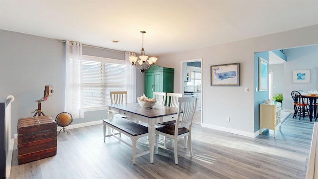 dining area featuring baseboards, light wood-type flooring, and a notable chandelier