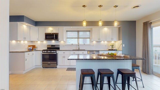 kitchen featuring appliances with stainless steel finishes, white cabinets, a sink, and a breakfast bar area