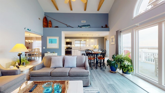 living area featuring high vaulted ceiling, visible vents, light wood finished floors, and an inviting chandelier