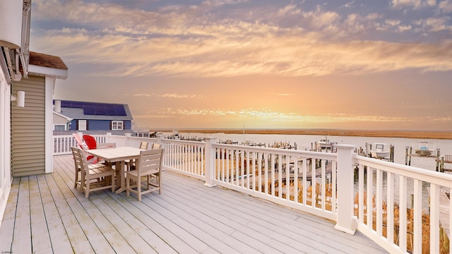 deck with outdoor dining area and a water view