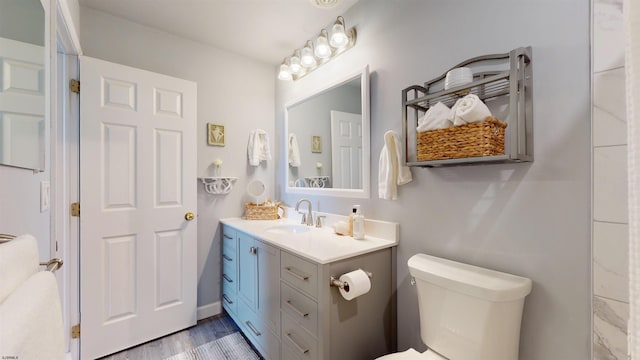 bathroom with toilet, wood finished floors, and vanity