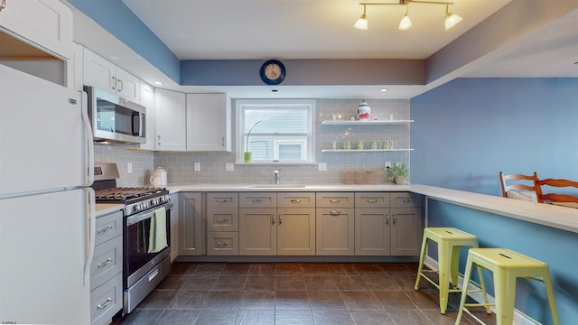 kitchen with stainless steel appliances, light countertops, a sink, and decorative backsplash