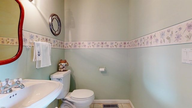 half bathroom featuring visible vents, a sink, toilet, and tile patterned floors