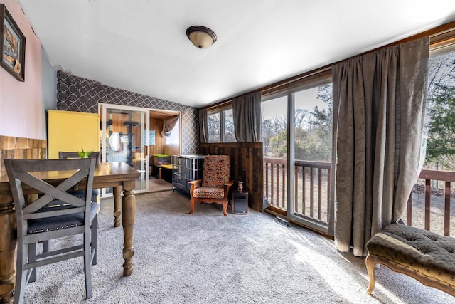 living area featuring carpet floors, lofted ceiling, visible vents, and wallpapered walls