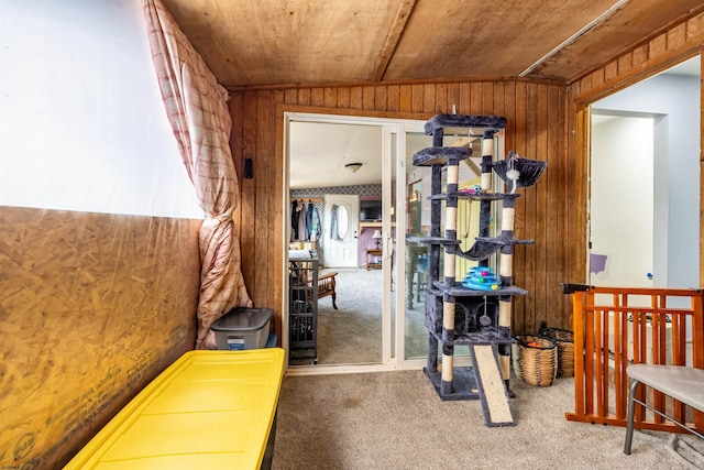 hall featuring wooden ceiling, carpet, wooden walls, and vaulted ceiling