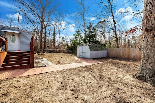 view of yard with a shed, a fenced backyard, and an outbuilding