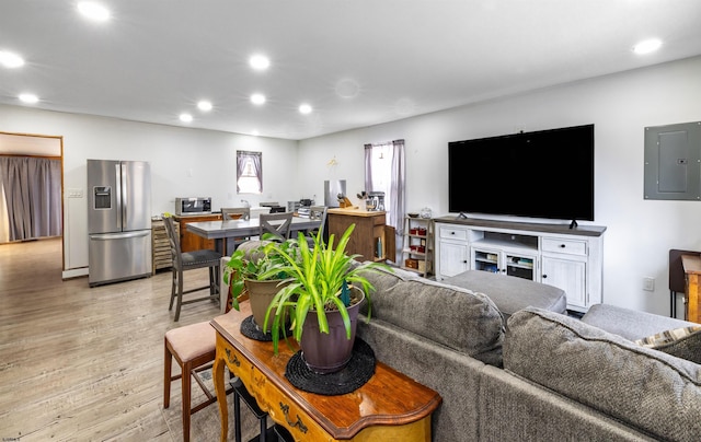 living area with light wood-style floors, electric panel, and recessed lighting