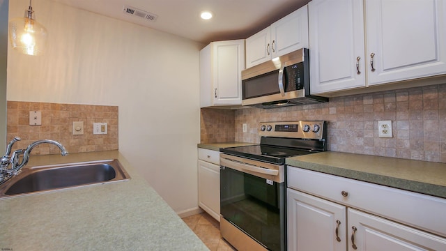 kitchen featuring hanging light fixtures, appliances with stainless steel finishes, white cabinets, and a sink