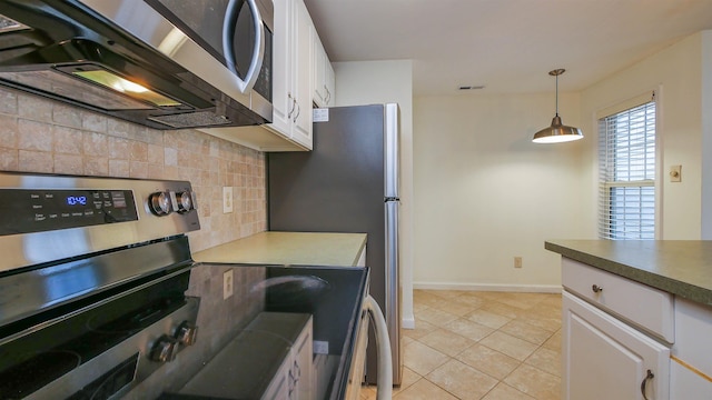 kitchen with appliances with stainless steel finishes, white cabinetry, light countertops, and decorative light fixtures