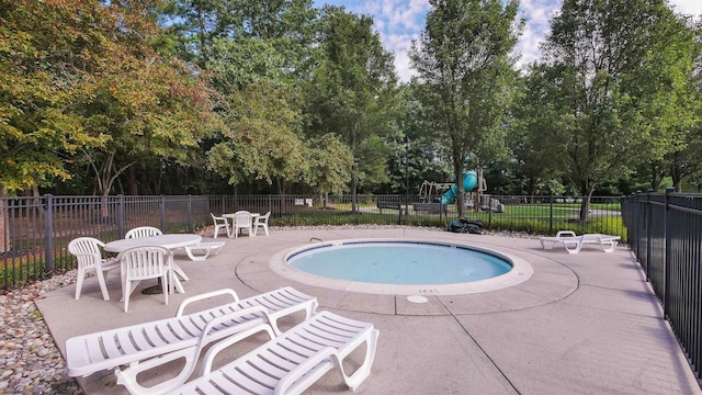 pool with fence, playground community, and a patio