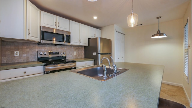 kitchen featuring light tile patterned floors, stainless steel appliances, decorative backsplash, white cabinets, and a sink