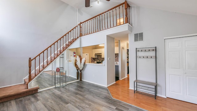 interior space with high vaulted ceiling, baseboards, visible vents, and wood finished floors