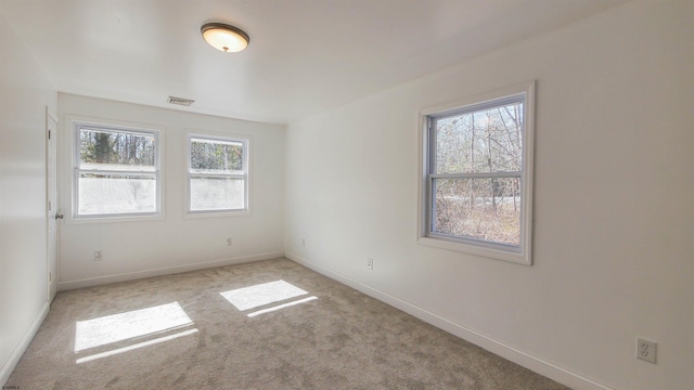 unfurnished room with baseboards, visible vents, and light colored carpet