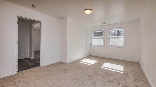 unfurnished room with light colored carpet, visible vents, and baseboards